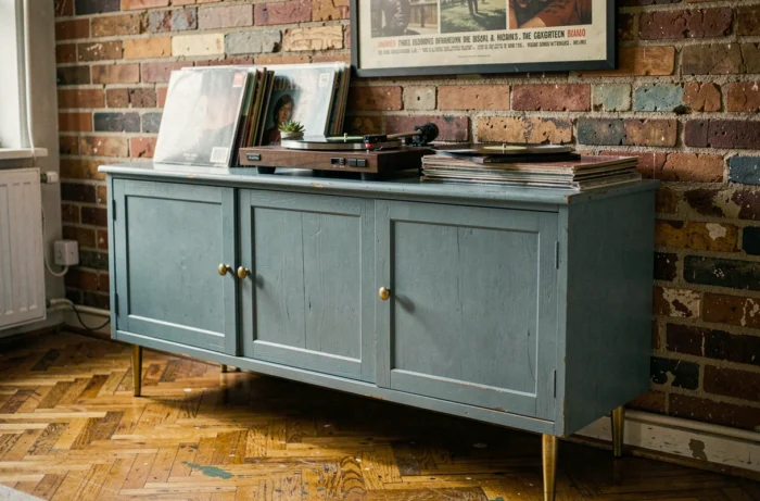 Meuble de seconde main détourné en console vinyle, repeint en bleu avec pieds en laiton, stylisté dans un appartement éclectique